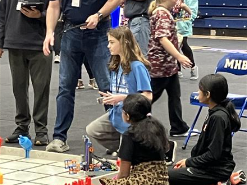 A girl holds a controller to a robot.